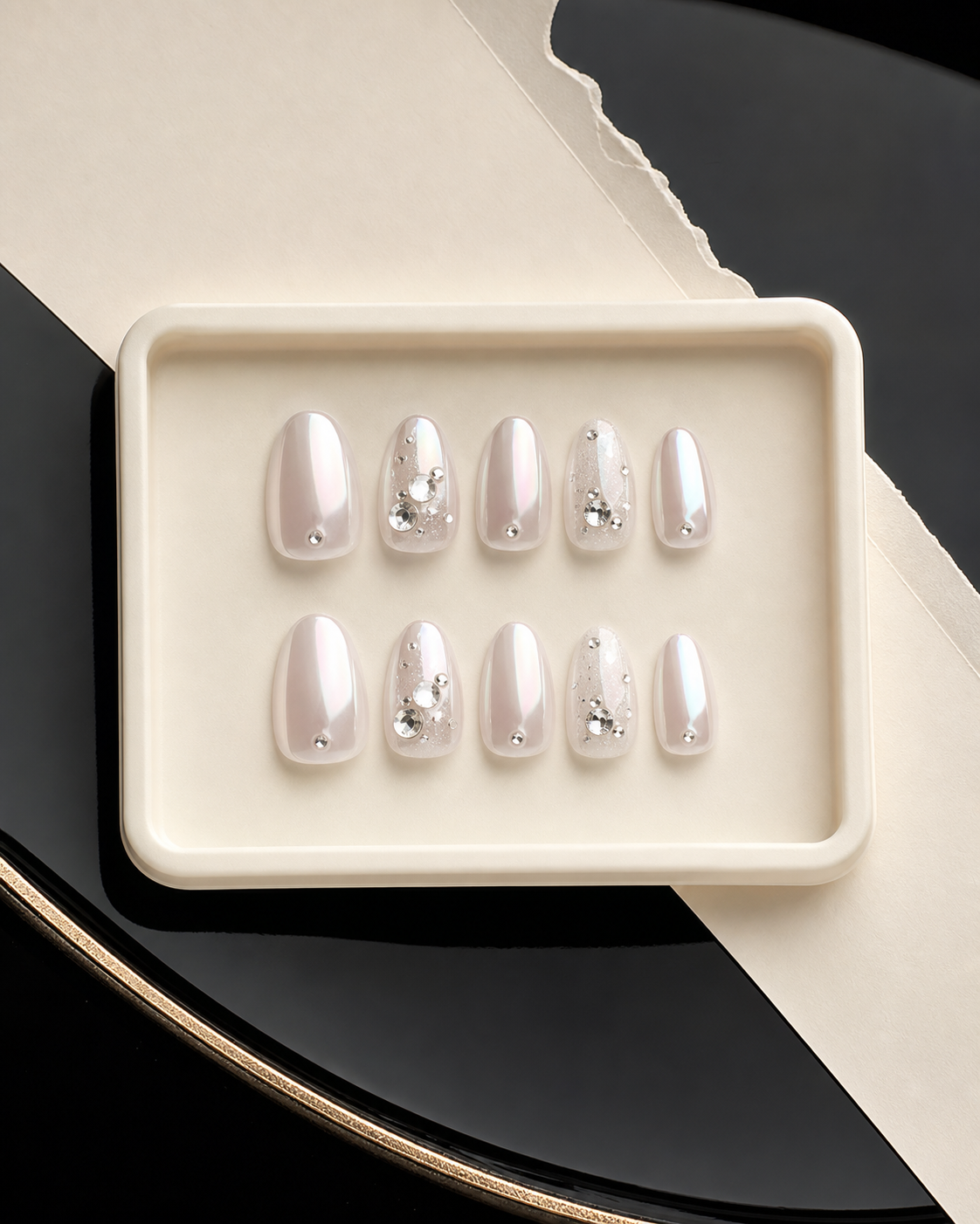 Pearly chrome almond press-on nails with crystal details in an ivory presentation box